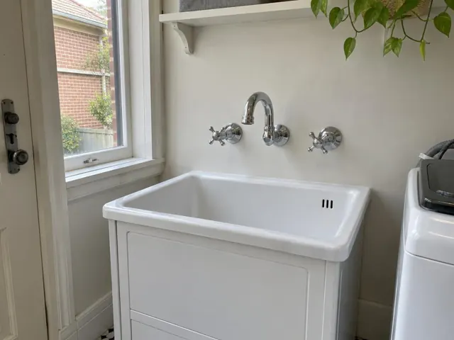 White laundry sink with chrome taps under a window in a home laundry in Freshwater